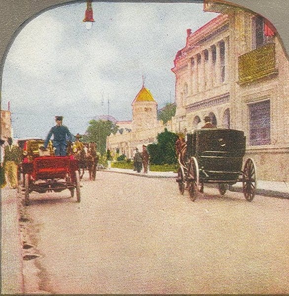 Postal coloreada de una calle del centro de la Ciudad de México con un automóvil abierto y carruajes tirados por caballos.